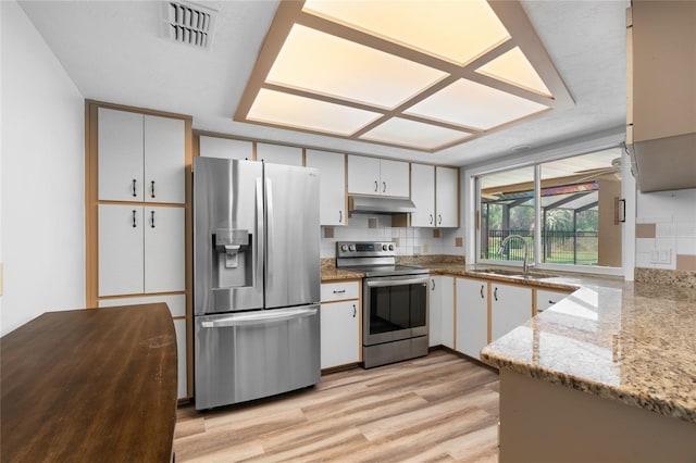 kitchen featuring light stone countertops, appliances with stainless steel finishes, decorative backsplash, sink, and white cabinetry