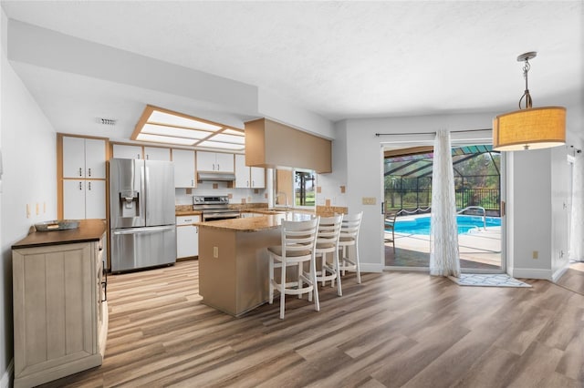 kitchen with pendant lighting, light wood-type flooring, white cabinetry, kitchen peninsula, and stainless steel appliances