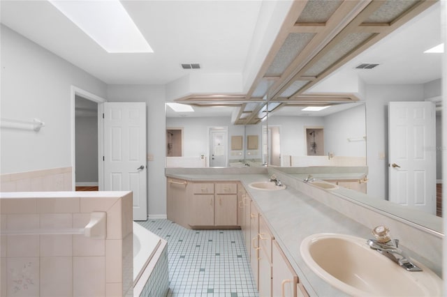 bathroom with tile patterned floors, vanity, a bathtub, and a skylight