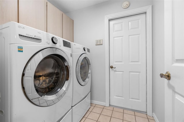 washroom featuring washer and clothes dryer, cabinets, and light tile patterned floors