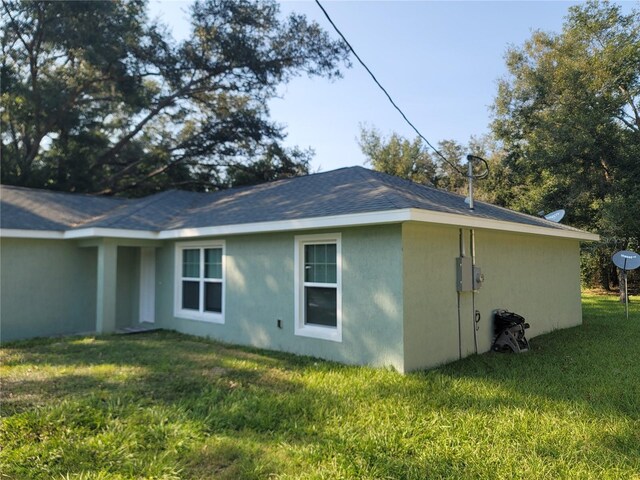 view of side of home featuring stucco siding and a yard