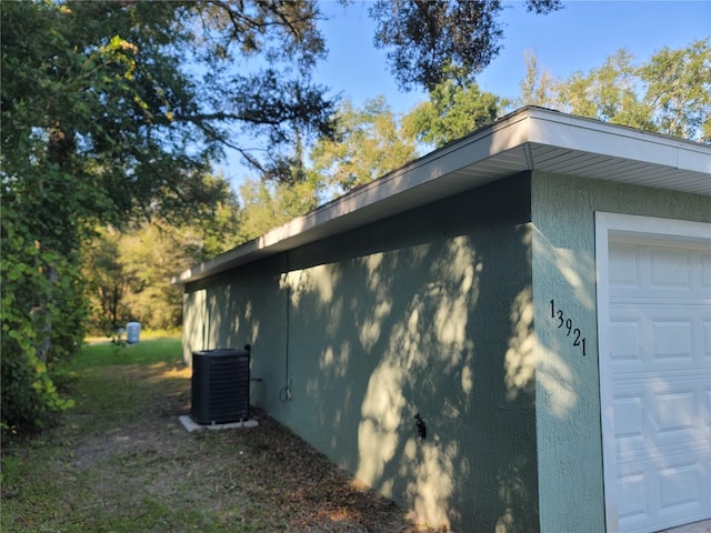 view of side of property featuring central AC unit and a garage