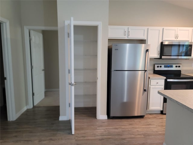 kitchen featuring light hardwood / wood-style flooring, appliances with stainless steel finishes, vaulted ceiling, and white cabinetry