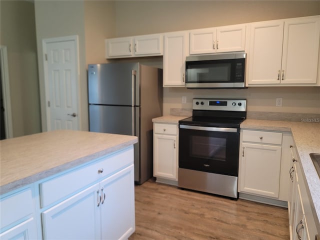 kitchen with stainless steel appliances, white cabinets, and light hardwood / wood-style flooring