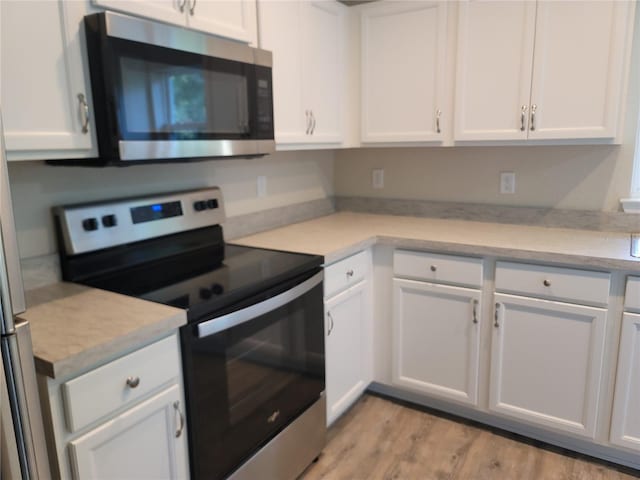 kitchen with appliances with stainless steel finishes, light hardwood / wood-style flooring, and white cabinetry