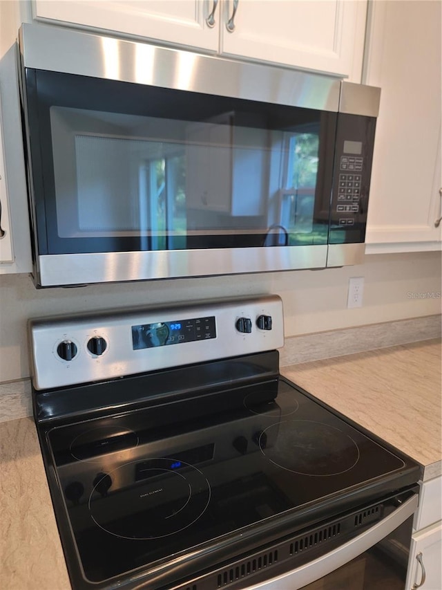 details with appliances with stainless steel finishes and white cabinetry