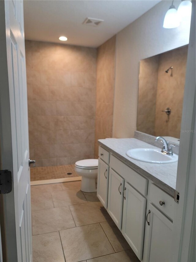 bathroom featuring tile patterned floors, vanity, toilet, visible vents, and tiled shower