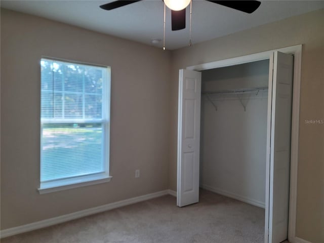 unfurnished bedroom featuring ceiling fan, a closet, and light carpet