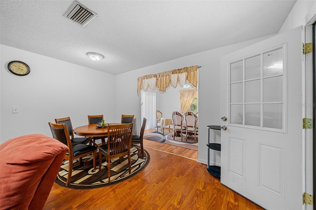 dining room featuring wood-type flooring and a textured ceiling