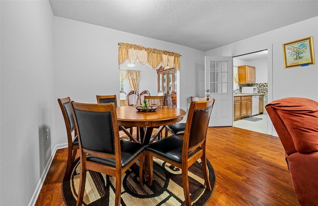 dining space featuring light hardwood / wood-style floors and a textured ceiling