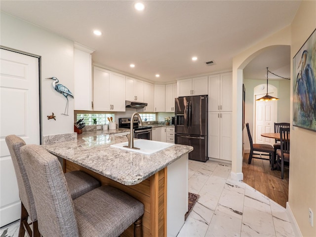 kitchen with a breakfast bar area, appliances with stainless steel finishes, kitchen peninsula, and white cabinetry