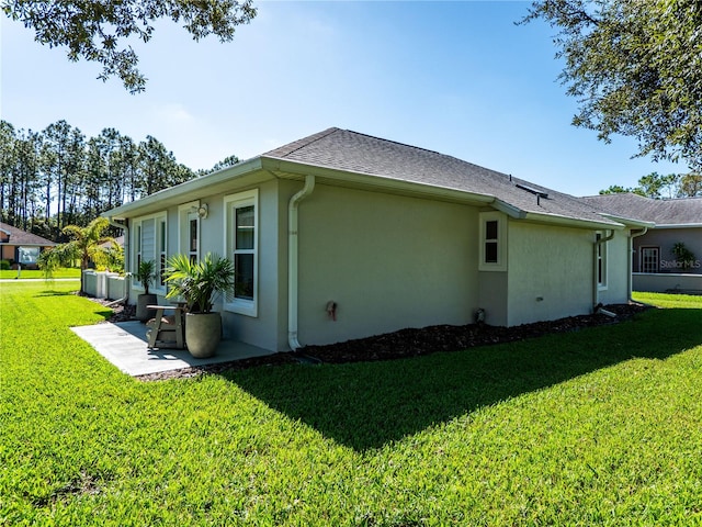 view of side of property with a patio area and a lawn