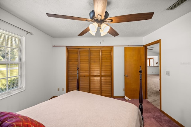 carpeted bedroom featuring ceiling fan, a textured ceiling, and a closet