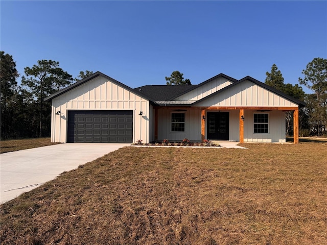 view of front of house with covered porch, a garage, and a front lawn