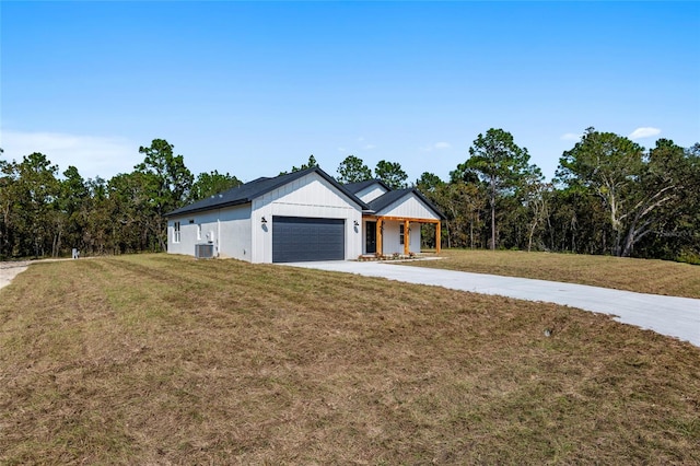 view of front of property featuring a front yard, central AC, a garage, and covered porch