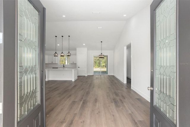 entrance foyer featuring wood-type flooring, sink, and vaulted ceiling