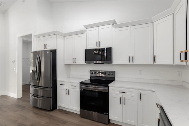 kitchen with dark hardwood / wood-style flooring, stainless steel appliances, white cabinetry, and light stone counters