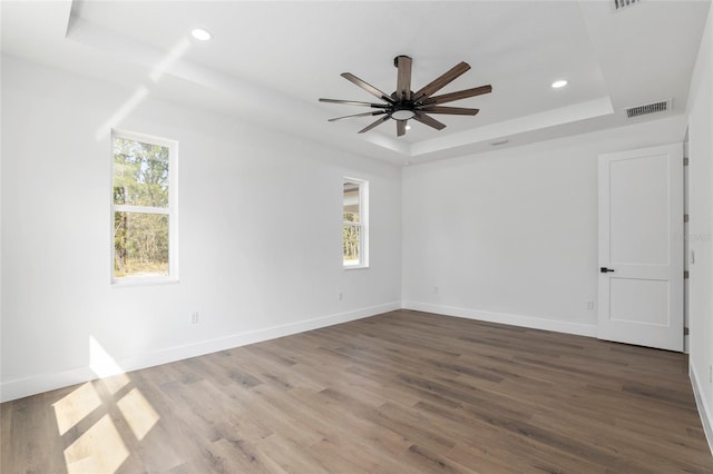 unfurnished room with wood-type flooring, a raised ceiling, and ceiling fan