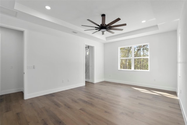 spare room featuring a raised ceiling, ceiling fan, and hardwood / wood-style flooring