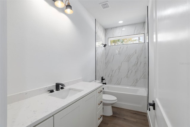 full bathroom with vanity, toilet, wood-type flooring, and tiled shower / bath