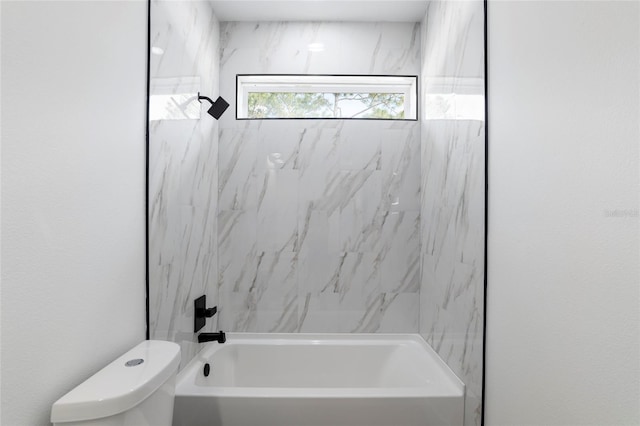 bathroom featuring tiled shower / bath combo and toilet