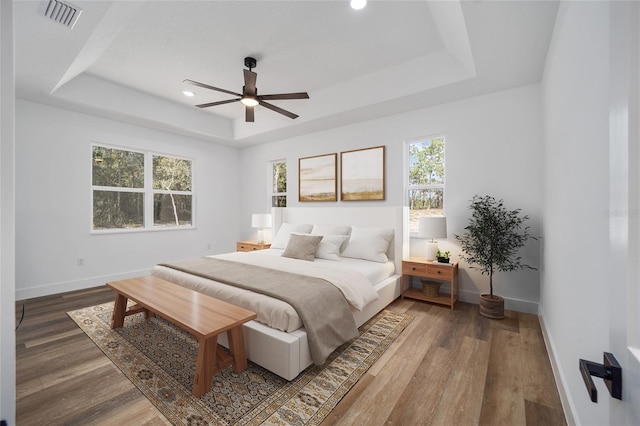 bedroom with multiple windows, ceiling fan, and wood-type flooring