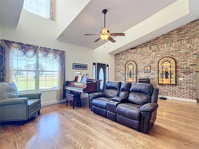 living room with a fireplace, light hardwood / wood-style floors, ceiling fan, vaulted ceiling, and brick wall