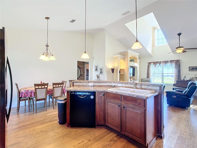 kitchen with black dishwasher, sink, light wood-type flooring, pendant lighting, and high vaulted ceiling