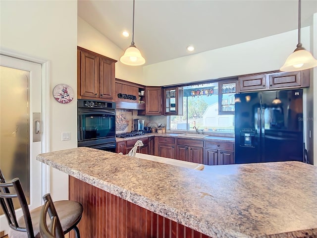 kitchen with a breakfast bar area, lofted ceiling, decorative light fixtures, and black fridge