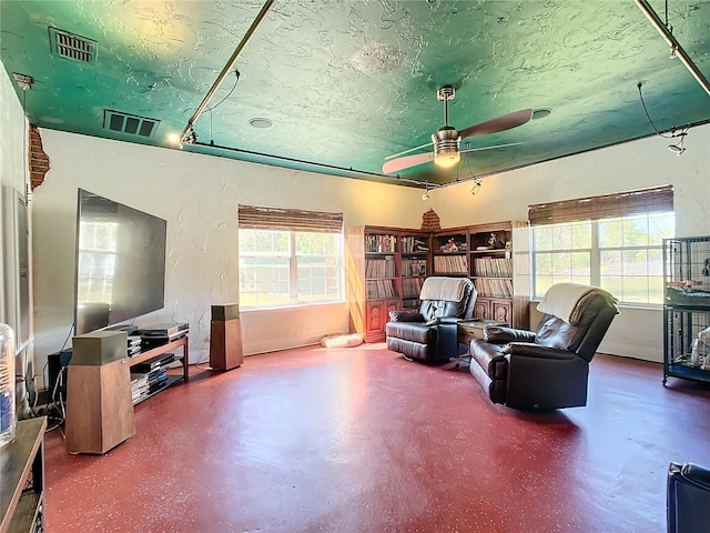 living room with a textured ceiling, concrete floors, and ceiling fan