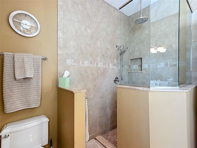 bathroom featuring a tile shower and toilet