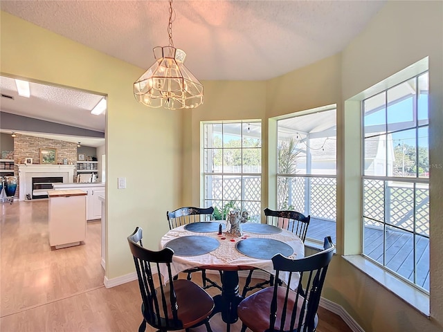 dining area with light hardwood / wood-style floors, a textured ceiling, a wealth of natural light, and an inviting chandelier