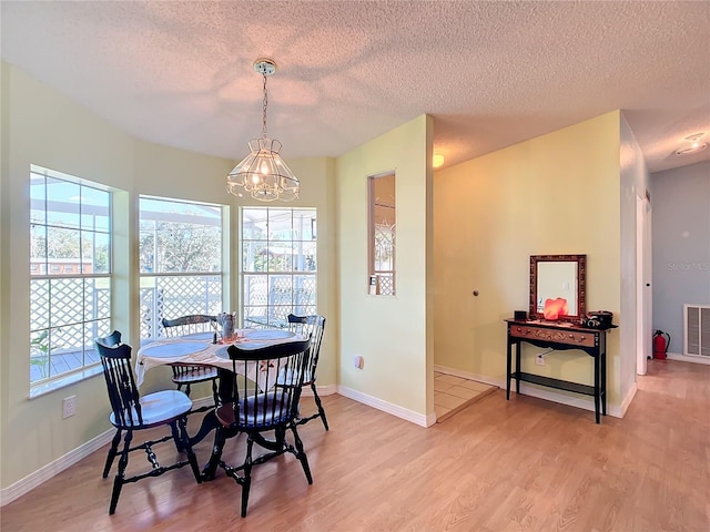 dining room featuring a textured ceiling, wood-type flooring, and a chandelier