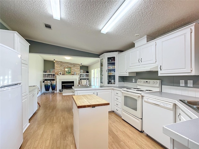 kitchen with butcher block counters, vaulted ceiling, white appliances, and white cabinets