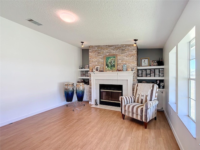 sitting room with a fireplace, a textured ceiling, and light wood-type flooring