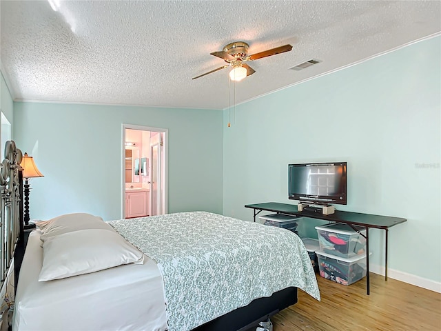 bedroom with a textured ceiling, ceiling fan, vaulted ceiling, connected bathroom, and light hardwood / wood-style flooring