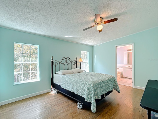 bedroom with light wood-type flooring, a textured ceiling, ceiling fan, vaulted ceiling, and connected bathroom