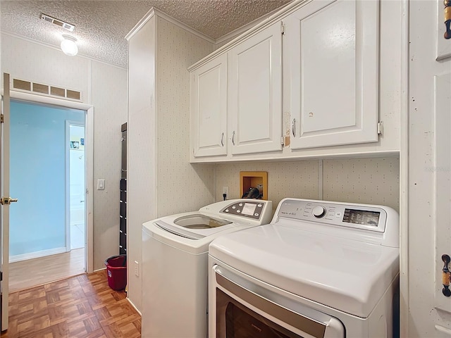 clothes washing area with independent washer and dryer, a textured ceiling, cabinets, and light parquet floors