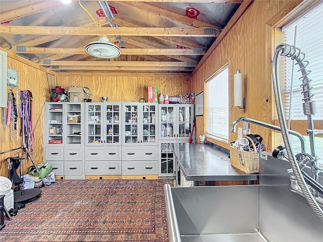 kitchen featuring a healthy amount of sunlight, lofted ceiling with beams, and wooden walls