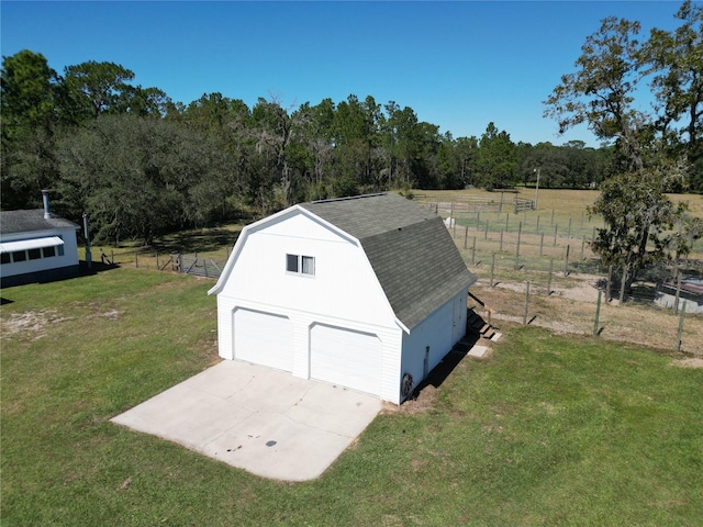 view of outbuilding featuring a garage, a lawn, and a rural view