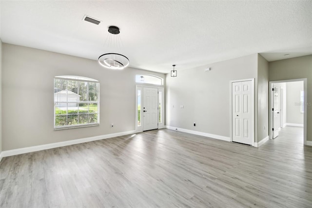 unfurnished room featuring a textured ceiling, wood-type flooring, and an inviting chandelier