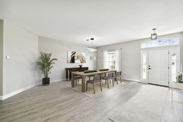 dining area featuring a textured ceiling and light hardwood / wood-style floors