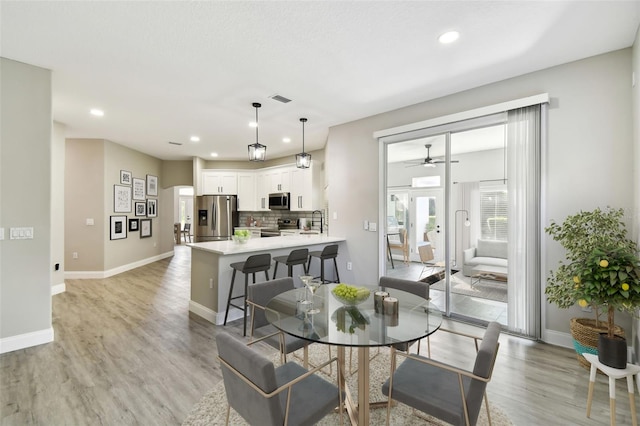 dining space with light hardwood / wood-style flooring, sink, and ceiling fan