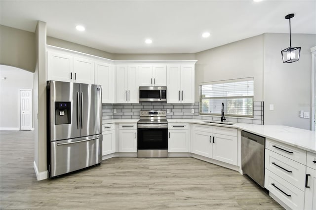 kitchen with white cabinetry, stainless steel appliances, sink, and light wood-type flooring