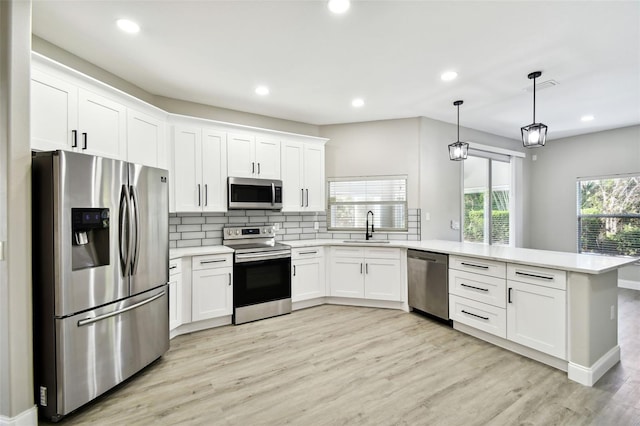 kitchen with white cabinetry, light hardwood / wood-style floors, stainless steel appliances, and decorative light fixtures