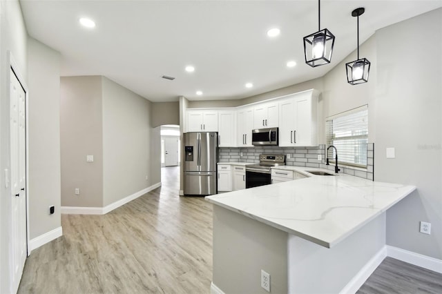 kitchen featuring stainless steel appliances, sink, decorative light fixtures, white cabinetry, and light hardwood / wood-style floors