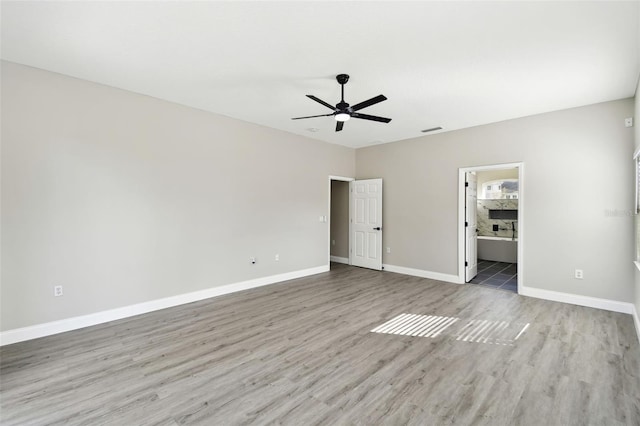 unfurnished bedroom with ensuite bath, light wood-type flooring, and ceiling fan