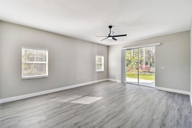 spare room with a wealth of natural light, a textured ceiling, light wood-type flooring, and ceiling fan