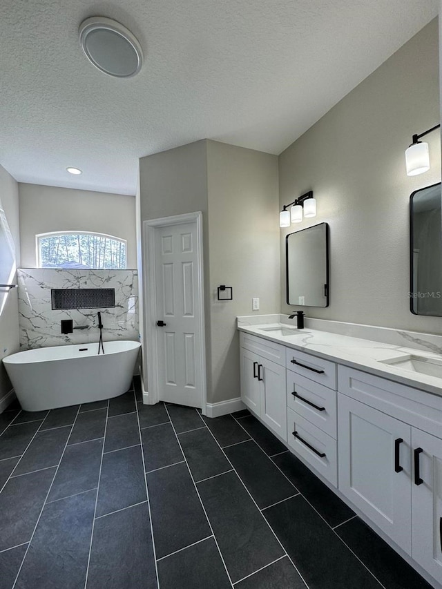 bathroom with vanity, a textured ceiling, a bathtub, and tile patterned flooring