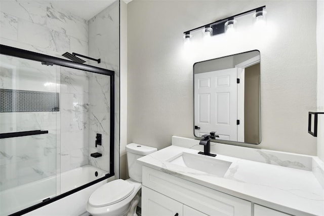 full bathroom featuring toilet, combined bath / shower with glass door, and vanity